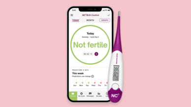 Natural Cycles App and thermometer showing 'not fertile' on phone screen